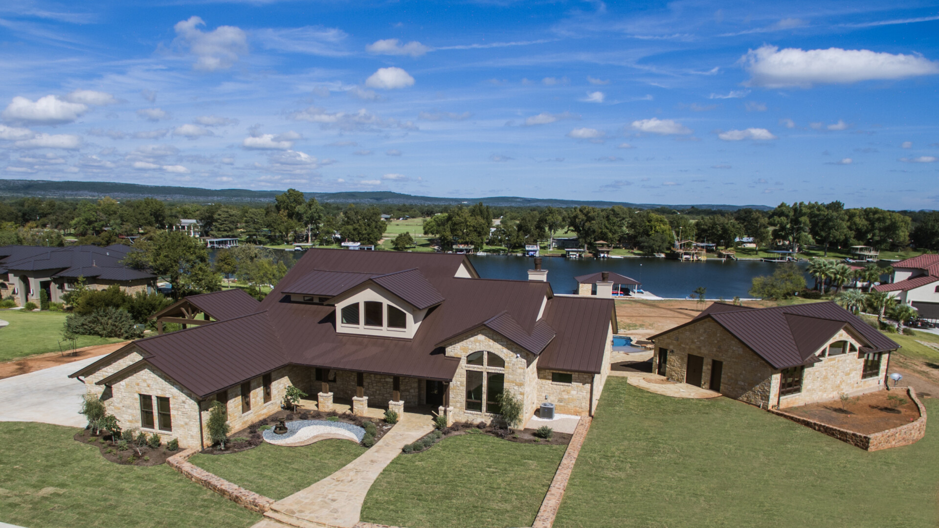 Aerial view of a custom home with a sophisticated stone exterior nestled on the lake, Lake LBJ TX